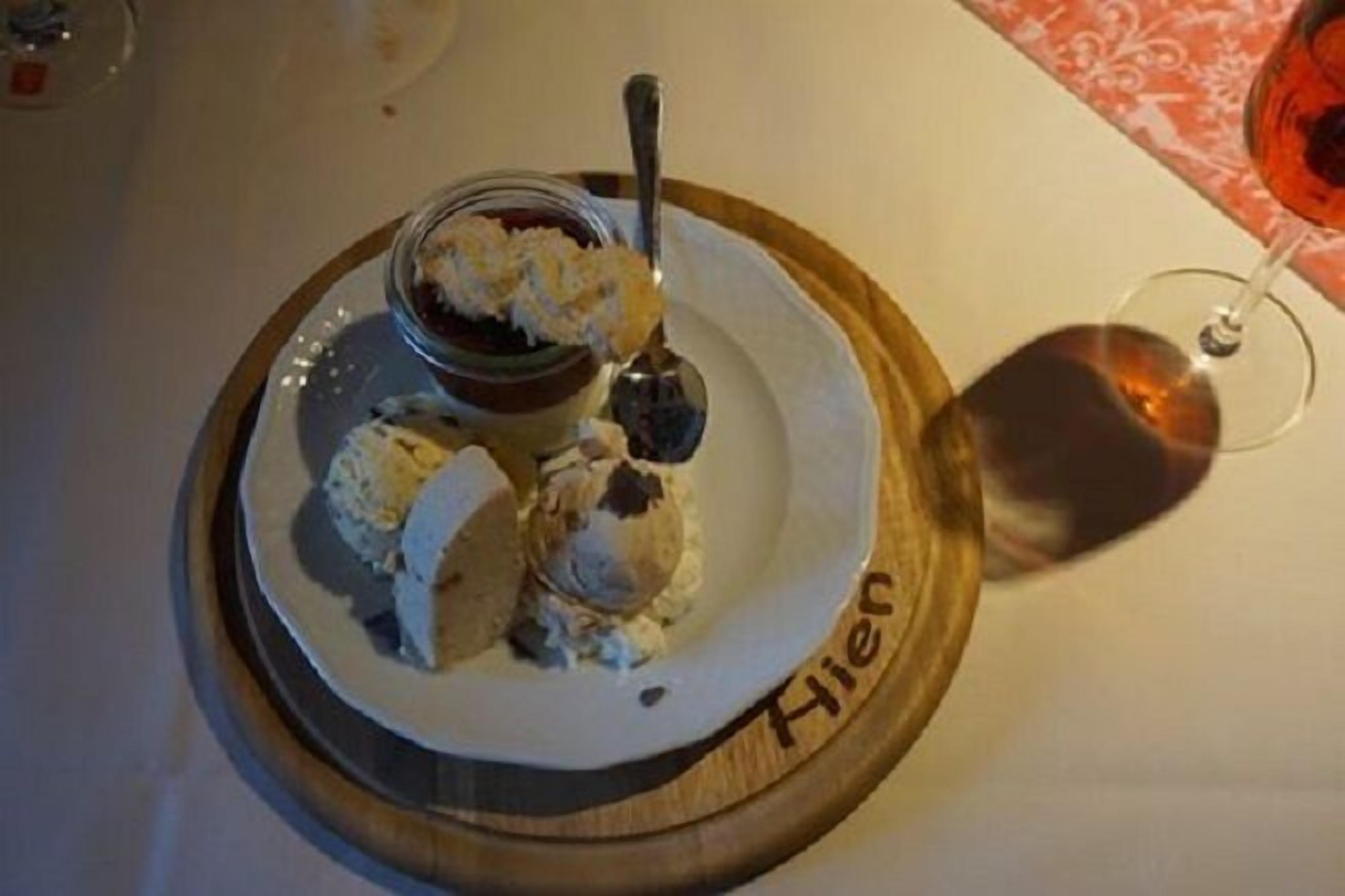 A dessert plate with ice cream and a spoon, placed on a wooden board with the name "Hien" on it.