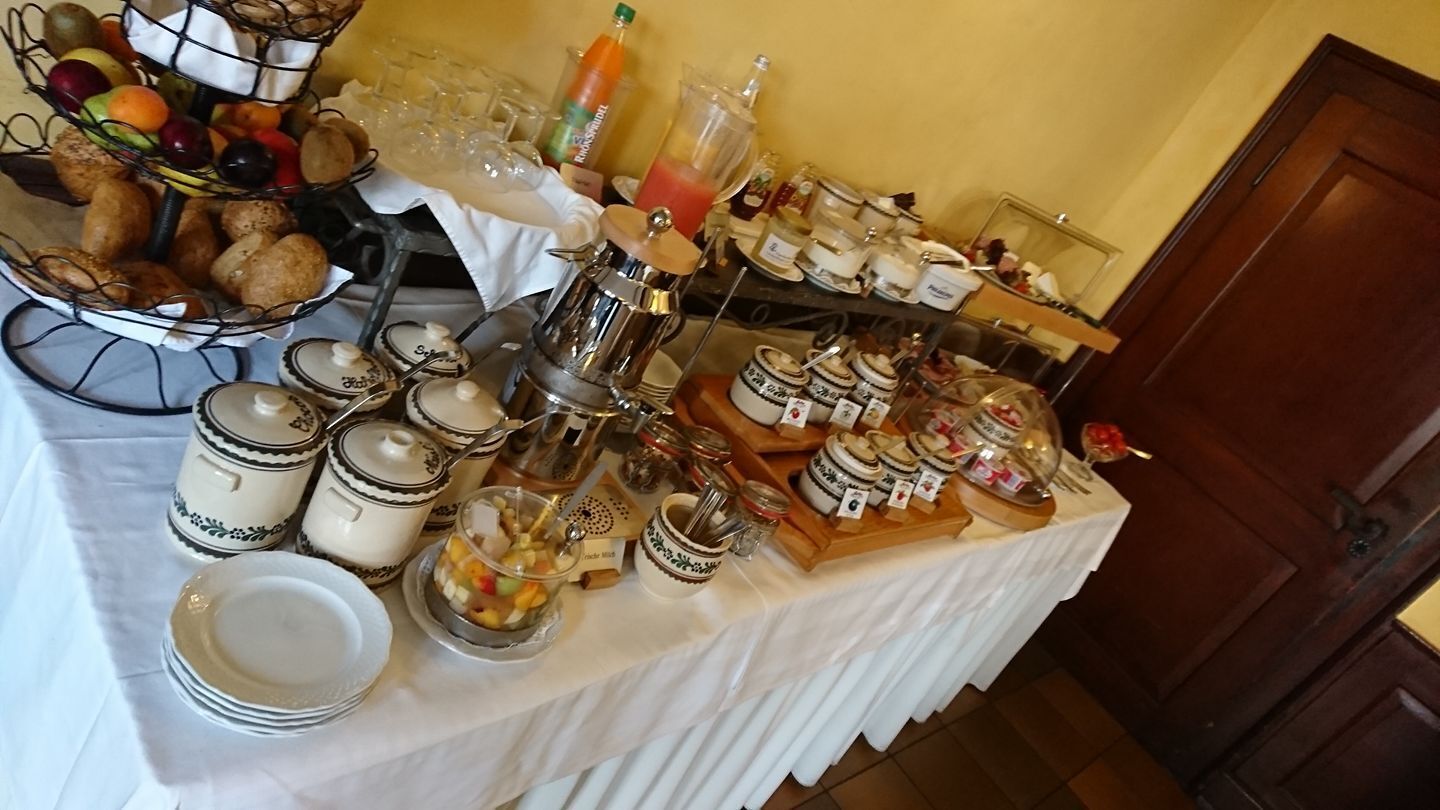 A buffet table with various food items, including fruits, pastries, and condiments.