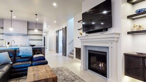 A modern living room with a fireplace, a flat-screen TV, a sofa, and a coffee table. - Steps to Pool | Lazy River | Waterslide | Poolside Villa | Arcadia #9 (Santa Clara)