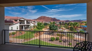 A hotel balcony with a view of a landscaped courtyard, buildings, and mountains. - Steps to Pool | Lazy River | Waterslide | Poolside Villa | Arcadia #9 (Santa Clara)