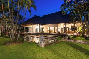 A modern house with a pool, surrounded by tropical vegetation.