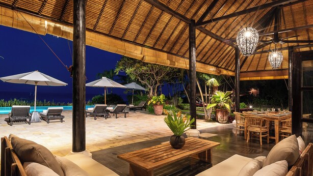 Un área de lounge al aire libre con piscina, asientos y comedor.