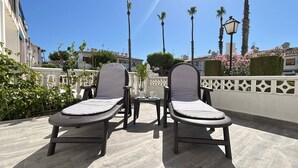 Two lounge chairs with striped cushions, a small table with a cup, and a decorative fence. - Ground floor bungalow LAGO JARDIN, LOS BALCONES, TORREVIEJA (Torrevieja)