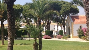 A well-maintained garden with palm trees and a building with a red-tiled roof. - Ground floor bungalow LAGO JARDIN, LOS BALCONES, TORREVIEJA (Torrevieja)