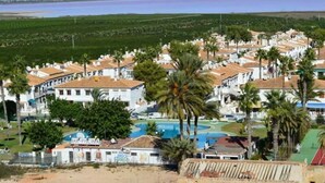 A coastal resort with white buildings, palm trees, and a swimming pool. - Ground floor bungalow LAGO JARDIN, LOS BALCONES, TORREVIEJA (Torrevieja)