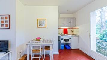 Un espacio habitable compacto con comedor, kitchenette y un amplio ventanal con vistas a zonas verdes.