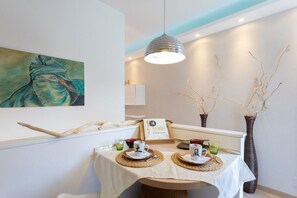Un coin repas avec une table dressée pour deux personnes, comprenant un menu de sushis, deux tasses et des branches décoratives.