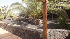 Un mur de pedra amb una estructura de pergola de fusta.