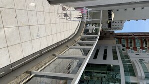 A modern building with a curved glass facade, a metal railing, and a clear view of the sky. - Lindo apto 70 m do mar (Centro)