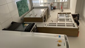 A kitchen with a gas stove, a microwave, and a built-in oven. There is a window with blinds and a view of the outside. - Lindo apto 70 m do mar (Centro)