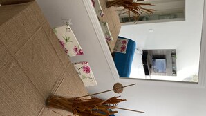 A living room with a sofa, a coffee table, and a decorative vase with dried branches. - Lindo apto 70 m do mar (Centro)