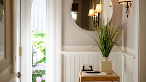 Un couloir avec une table en bois, un miroir et une plante en pot.