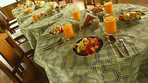 A breakfast setup with tables covered in patterned tablecloths, fruit bowls, and glasses of orange juice. - Huitoto Lake Lodge (Laberinto)