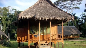 A wooden structure with a thatched roof, a hammock, and a wooden deck. - Huitoto Lake Lodge (Laberinto)
