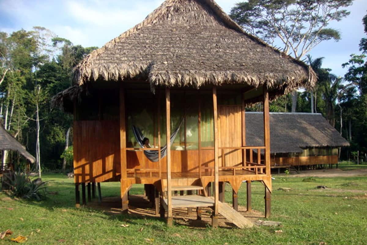 A wooden structure with a thatched roof, a hammock, and a wooden deck.