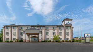 A multi-story hotel with a central entrance, a Bay Inn sign, and a parking lot. - Bay Inn & Suites Troy (Troy)