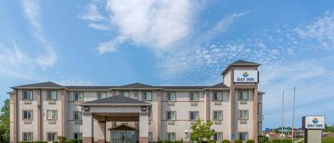 A multi-story hotel with a central entrance, a Bay Inn sign, and a parking lot.