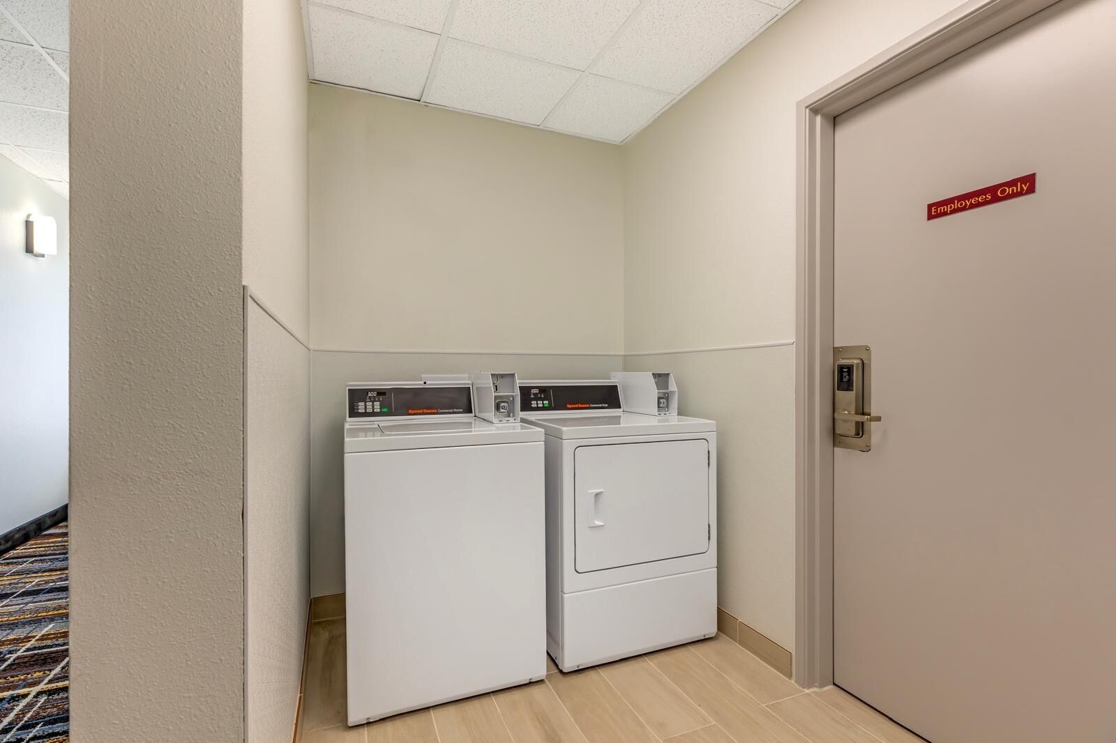 A laundry room with two front-loading washing machines and a door marked 'Employees Only'.