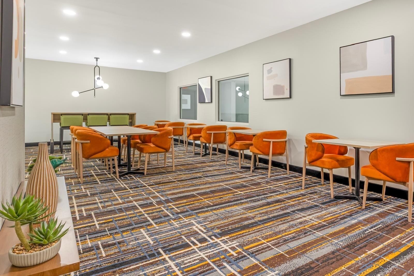A conference room with a patterned carpet, orange chairs, and a table.