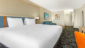 A hotel room with a large bed, a desk, a chair, and a carpeted floor. - Bay Inn & Suites Troy (Troy)