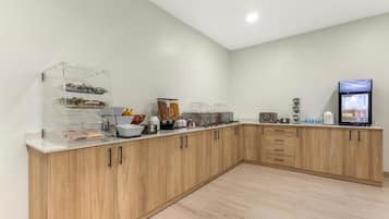 A modern kitchen with wooden cabinets, a glass display case, and various food items.