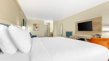 A hotel room with a large bed, a desk with a chair, a television, and a mirror.