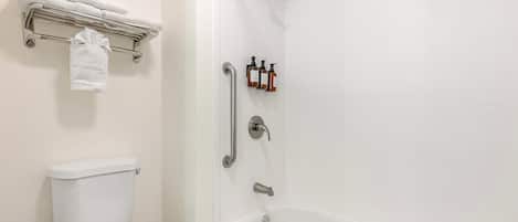 Un bagno con il water bianco, una vasca da bagno, una doccia con soffione manuale e una barra di sostegno.