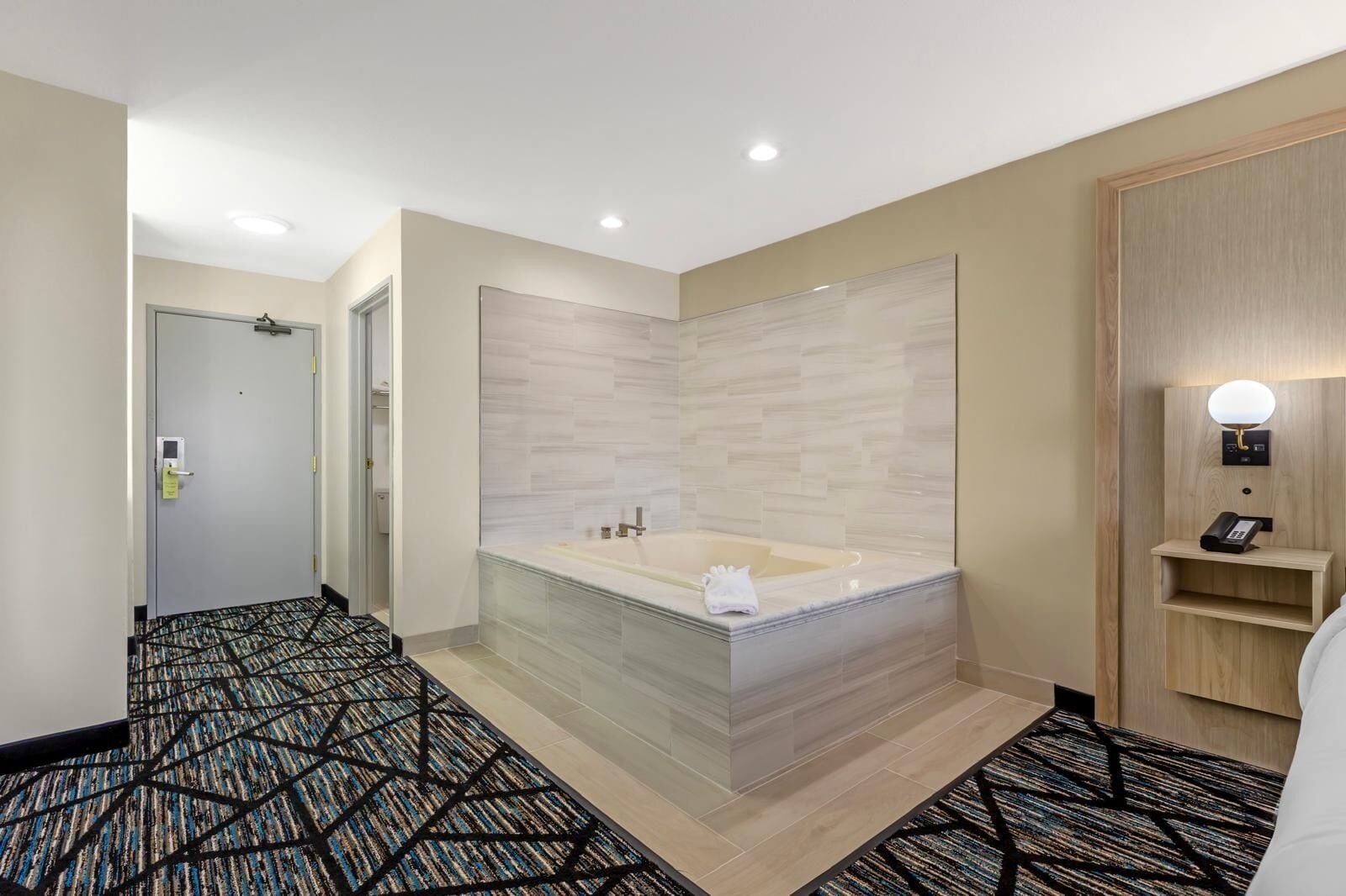 Un baño moderno con una bañera grande, un espejo y un tocador de madera.
