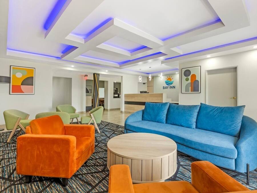 A hotel lobby with a reception desk, a blue sofa, and orange armchairs.