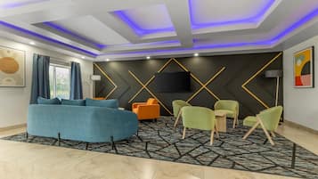 Un salon moderne avec un canapé, des fauteuils, un téléviseur à écran plat et un tapis à motifs.