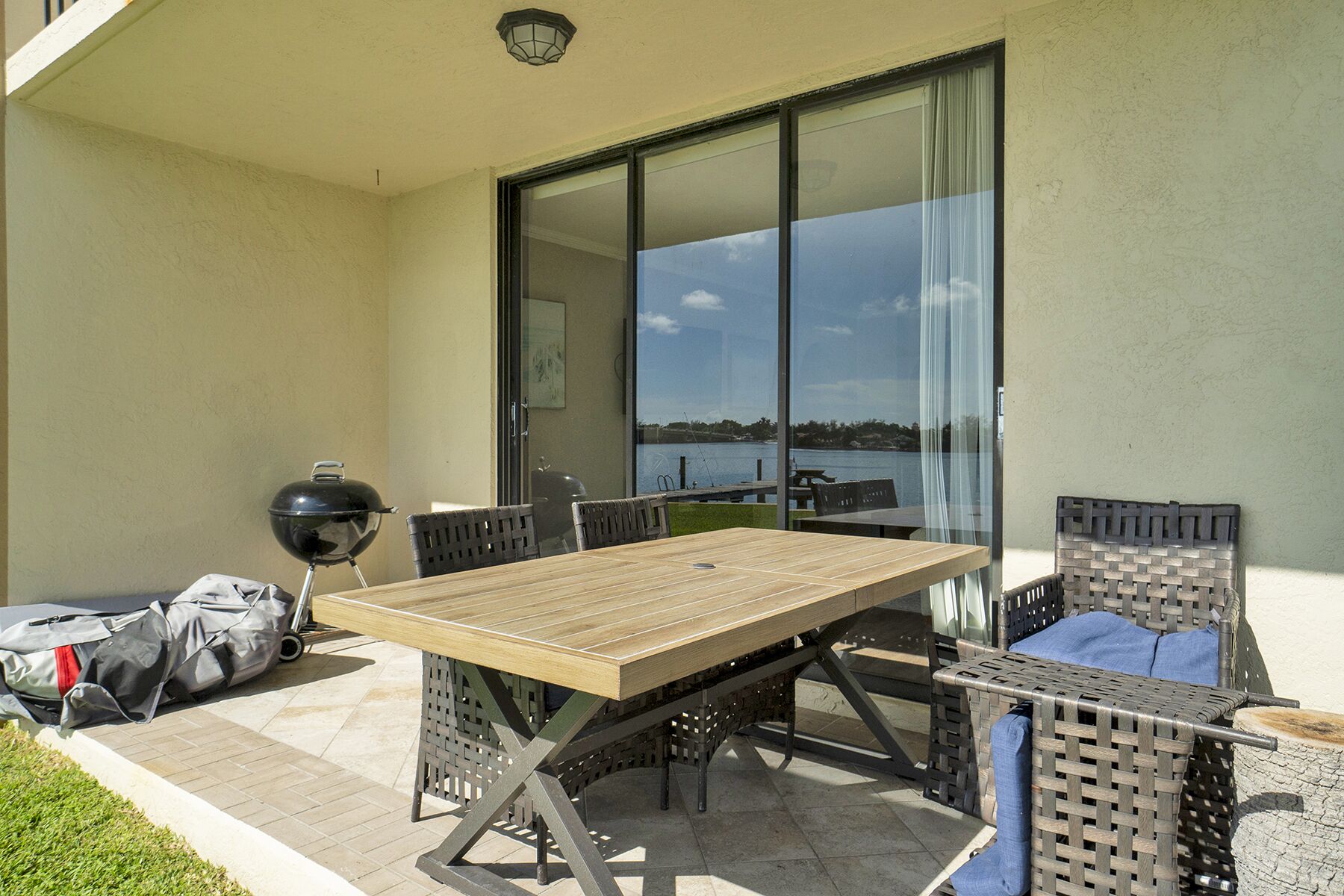Un patio con una mesa y sillas, una parrilla y vistas al agua.