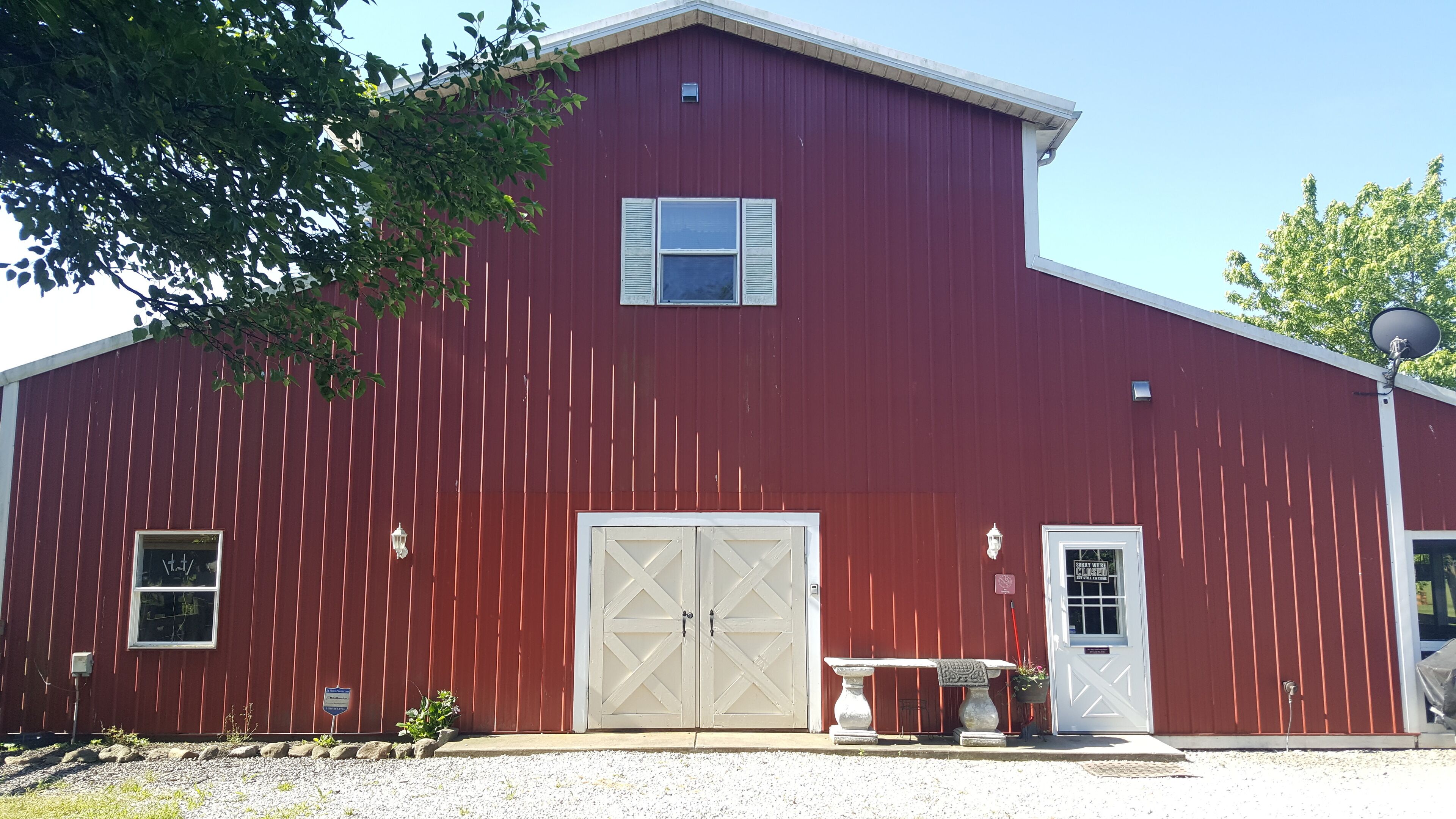 A red barn with a white door, a large garage door, and a small window with shutters.