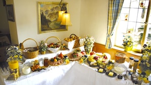 Une table dressée avec divers plats et boissons, un tableau accroché au mur et une fenêtre avec des rideaux.
