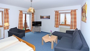 Une chambre d’hôtel avec un lit, deux canapés, une télévision et une table sur laquelle se trouve un vase.