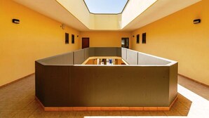 A modern interior with a central reception desk, a skylight, and a yellow wall. - Residence Ionian (Gallipoli)