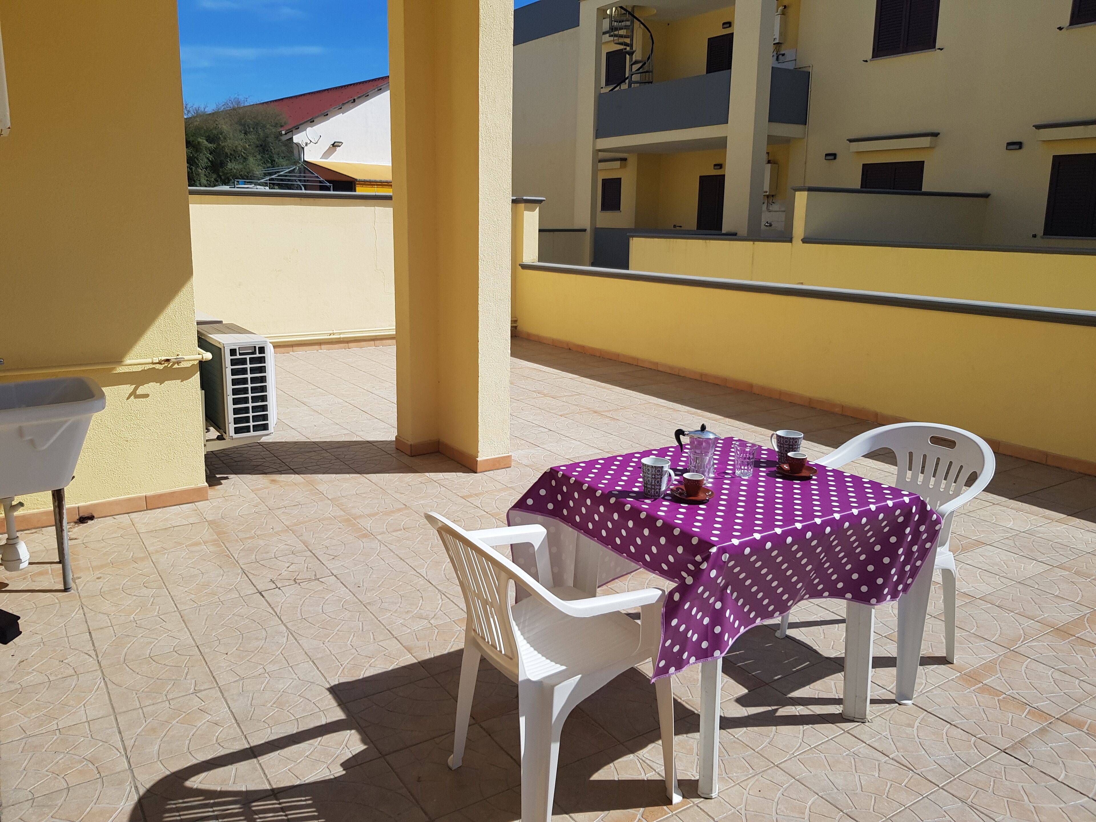 A patio with a table and chairs, a sink, and an air conditioning unit.