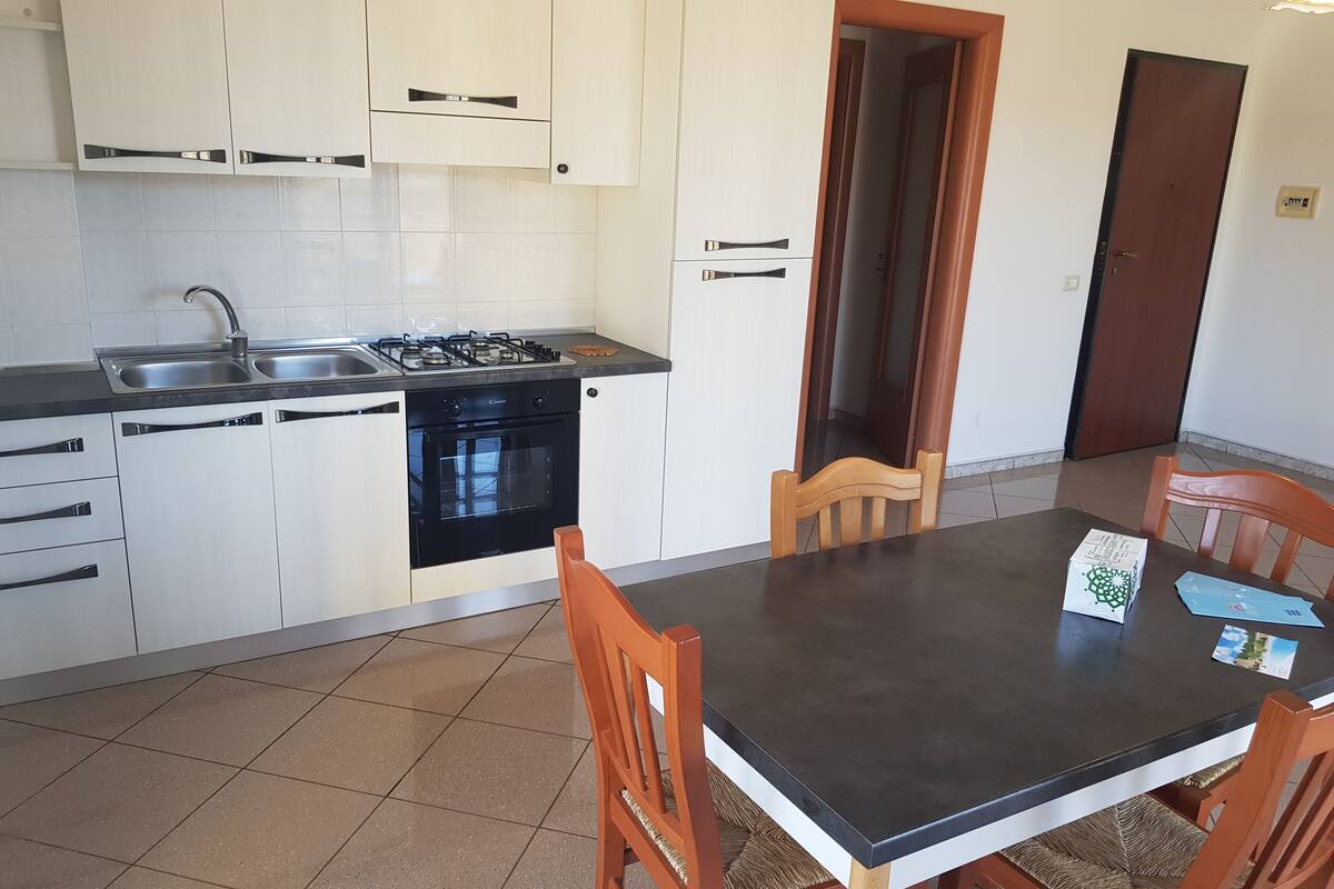 Una cocina con armarios blancos, una estufa negra y una mesa de comedor con sillas.