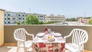 A balcony with a table set for two, chairs, and a view of buildings in the background. - Residence Ionian (Gallipoli)