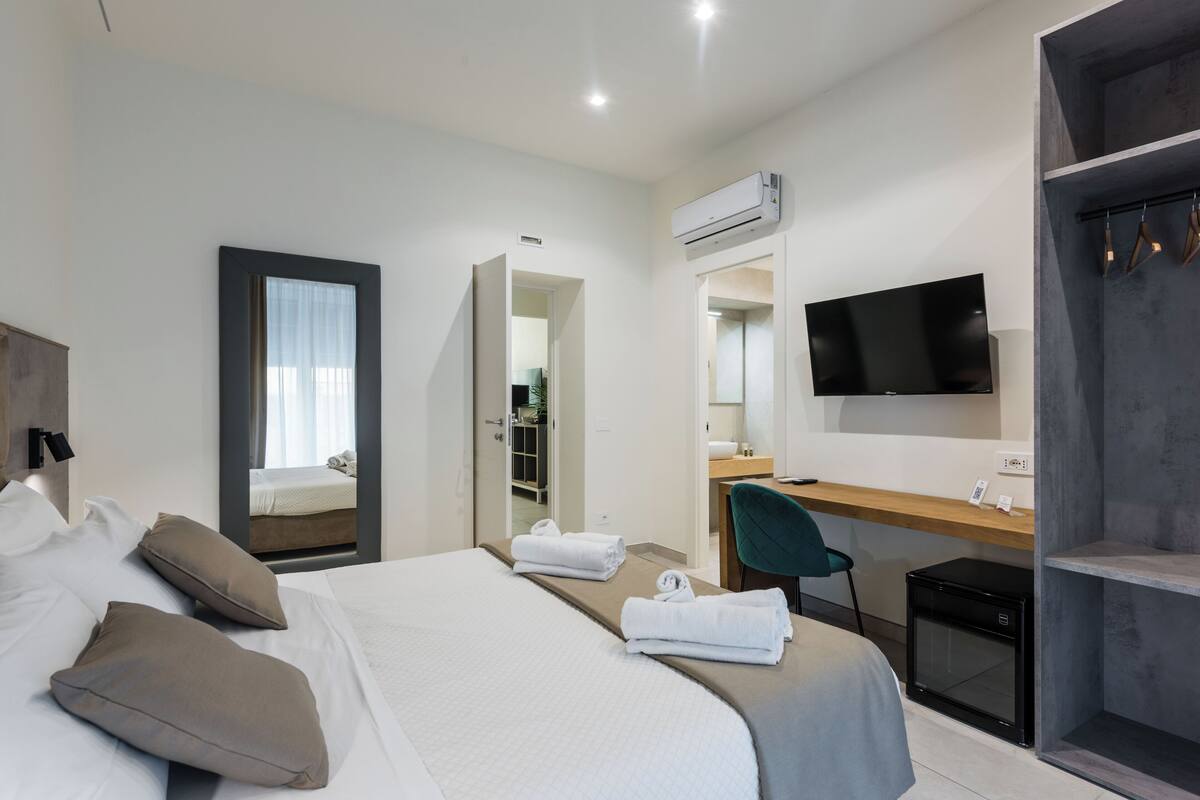 A hotel room with a bed, a desk, a TV, and a wardrobe.