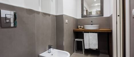 A modern bathroom with a bidet, a sink, and a mirror.