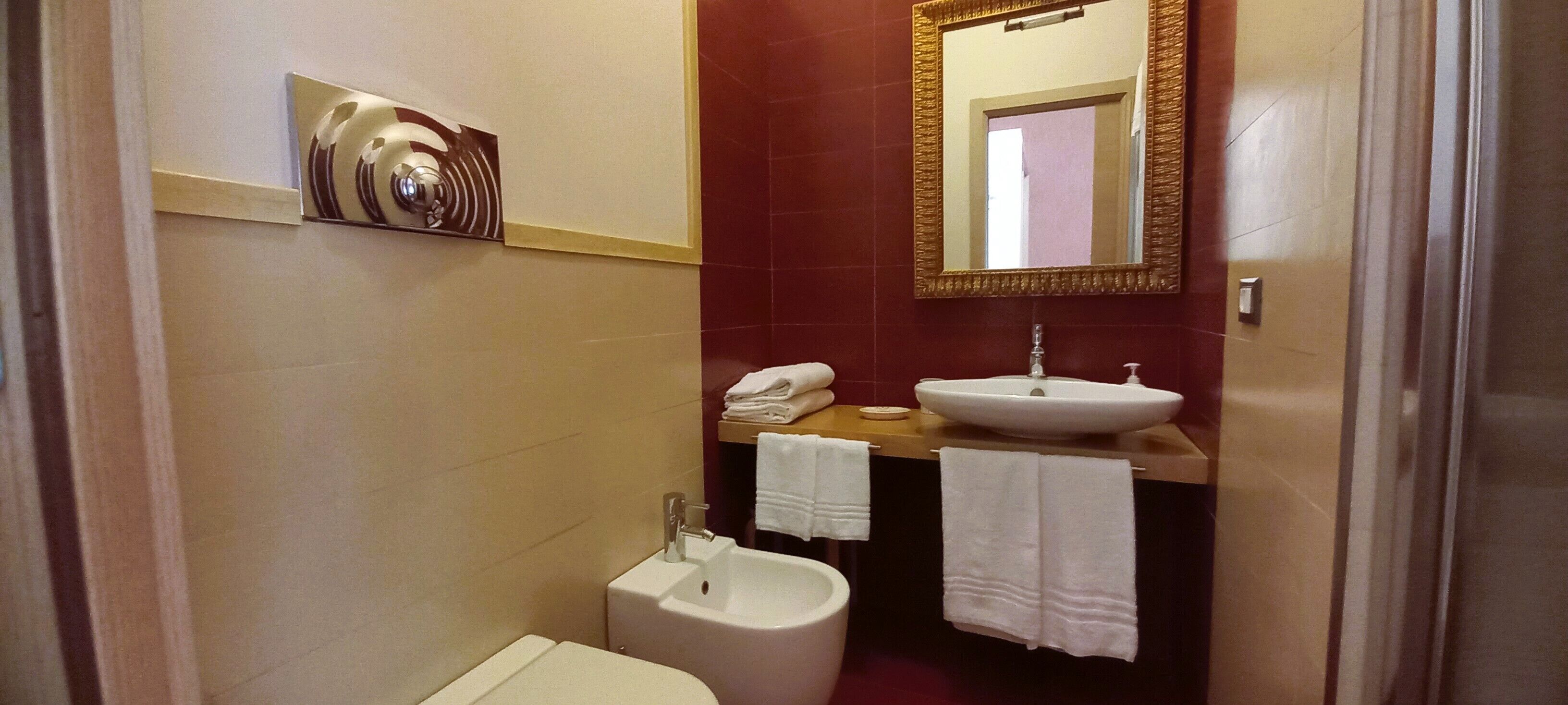 Une petite salle de bain comprenant des toilettes, un lavabo et un bidet. Un porte-serviettes permet d’accrocher deux serviettes.
