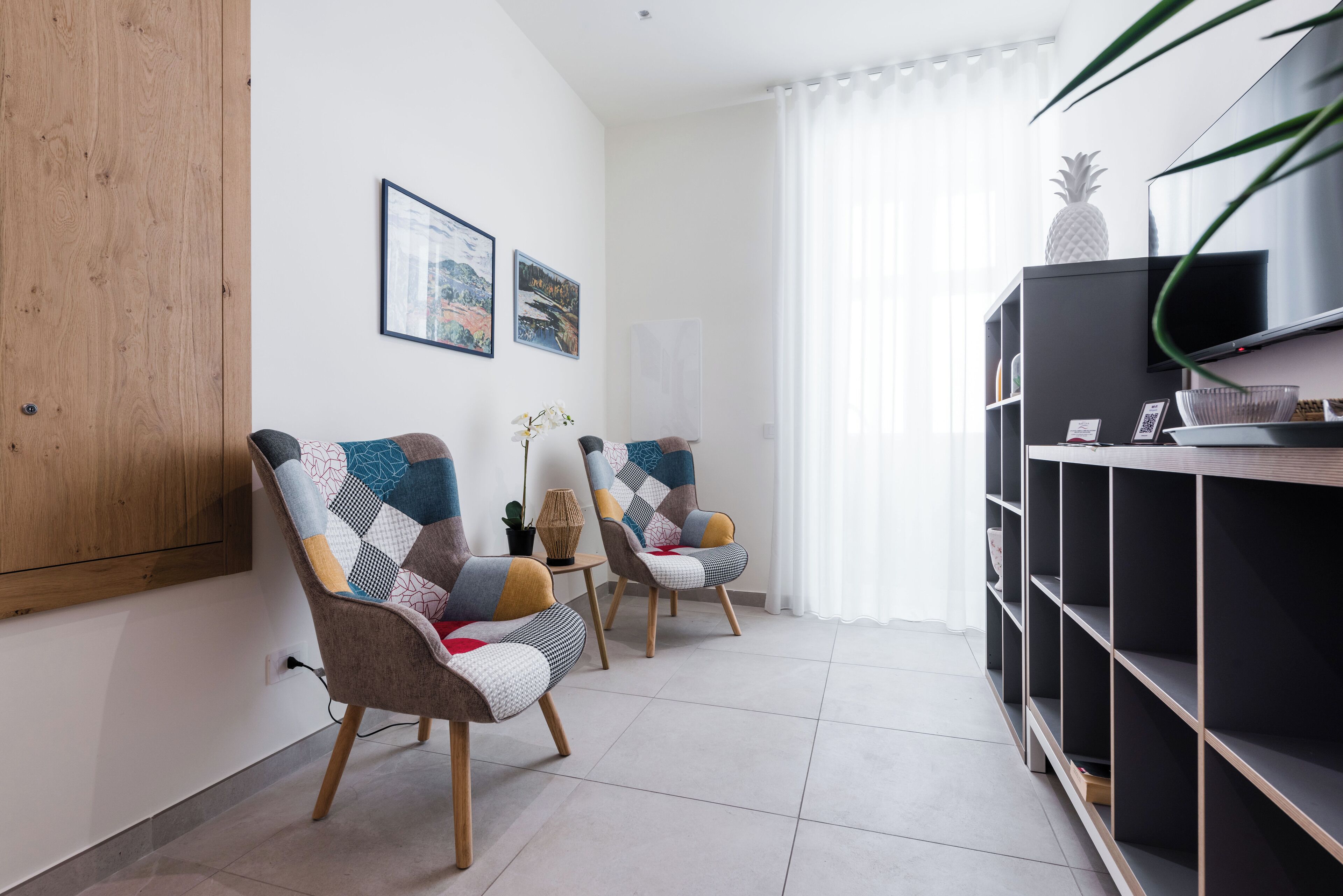 Una sala moderna con dos sillones, un aparador de madera y un mueble para televisión.
