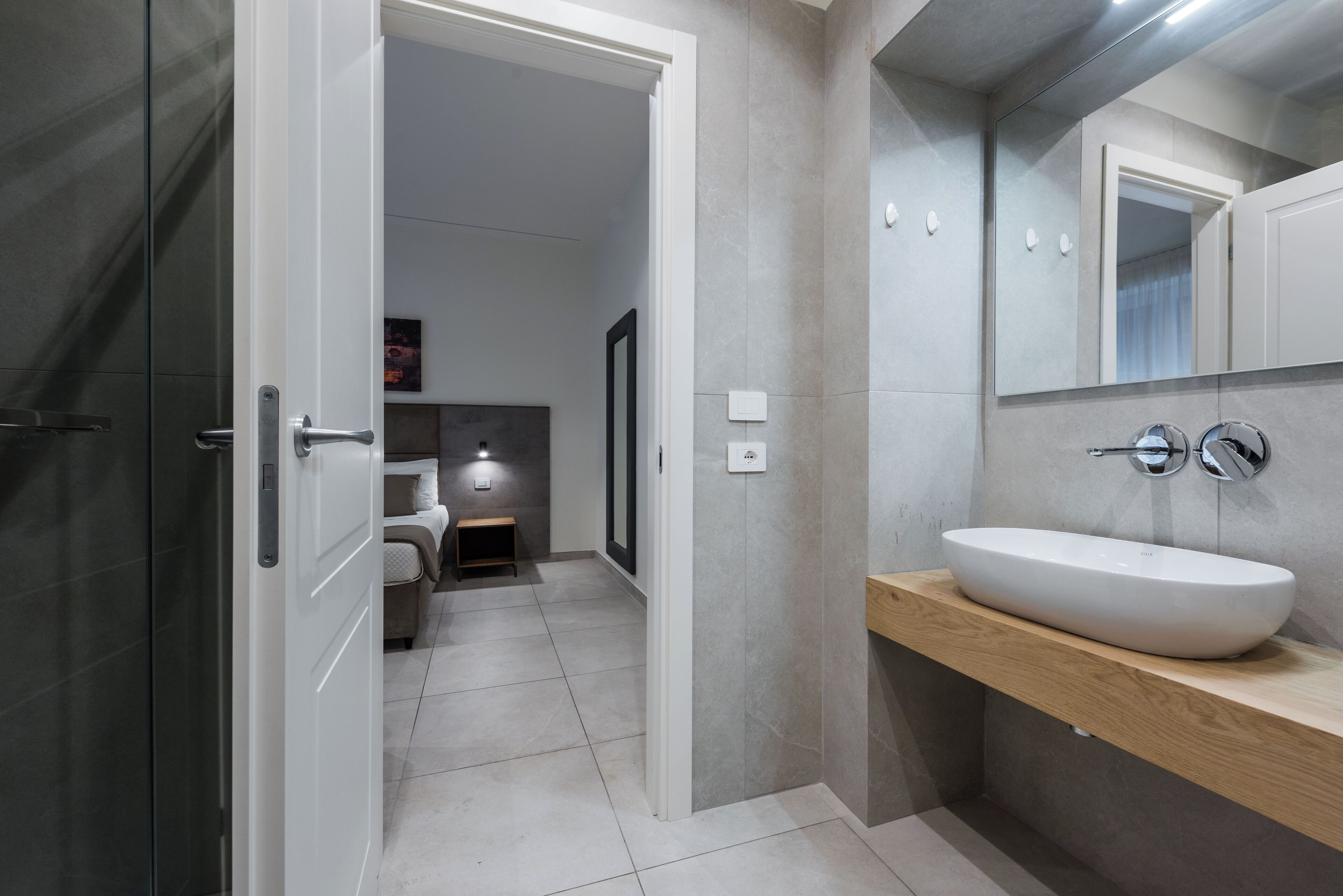 Een moderne badkamer met een groot wastafel, een spiegel en een deur naar een andere ruimte.