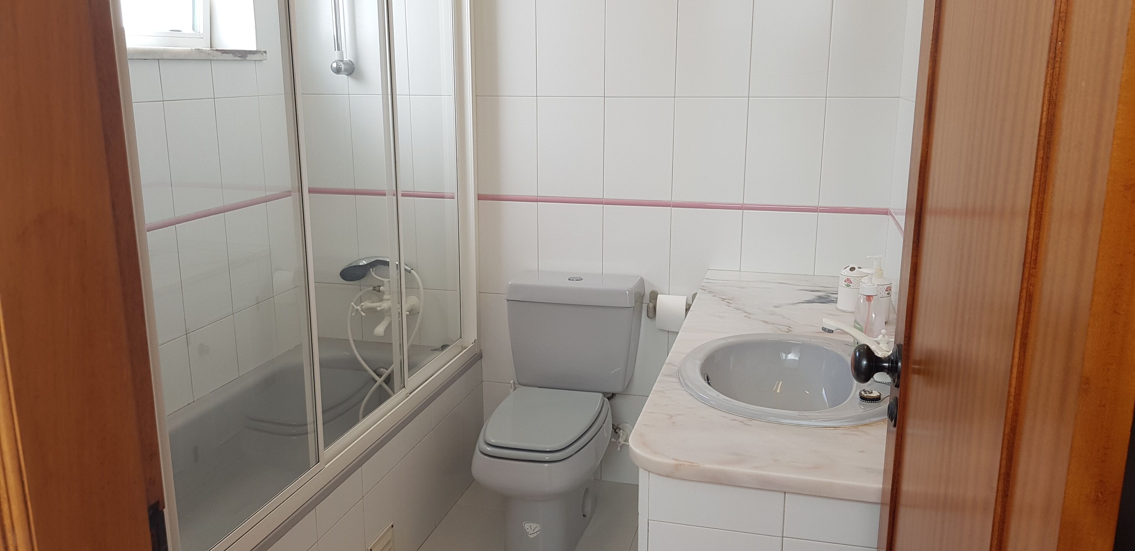 A small bathroom with a toilet, a sink, and a shower.