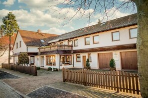 Ein traditionelles Gebäude im europäischen Stil mit Innenhof, Holzzaun und kleinem Garten.