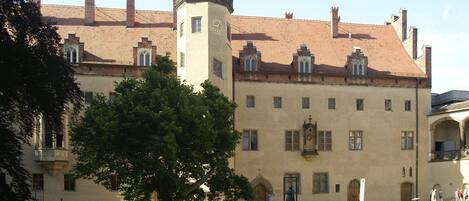 A historic building with a central tower, multiple windows, and a courtyard.