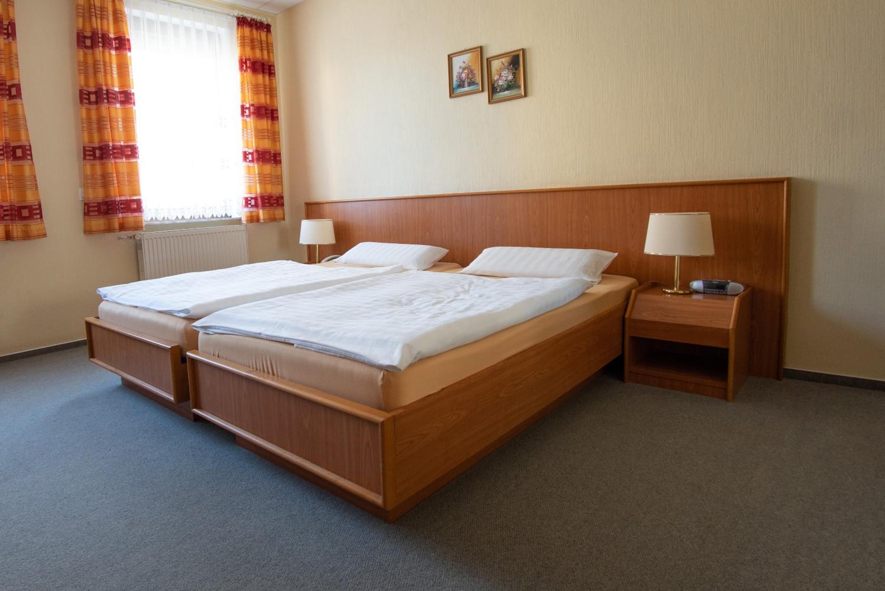 A double bed with wooden headboard, two bedside tables with lamps, and a window with curtains.