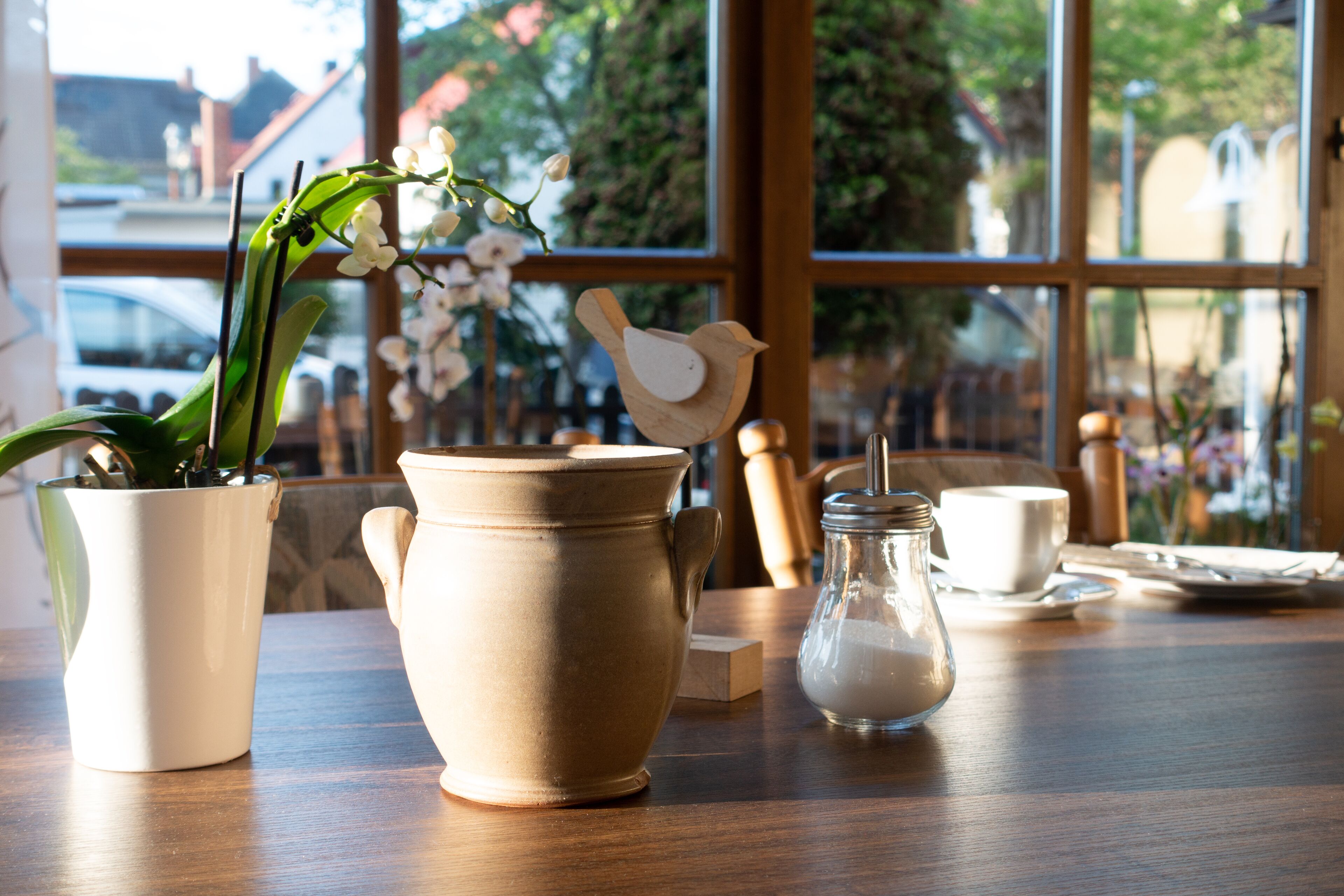 Une table avec un pot en céramique, un bocal en verre et une tasse en céramique.