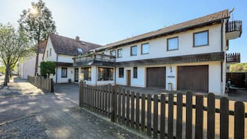 A two-story house with a wooden fence, a paved driveway, and a small garden area.