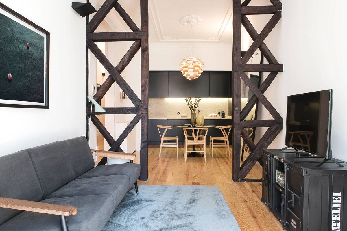Una sala de estar moderna con un sofá gris, una mesa de centro de madera y un tapete azul.